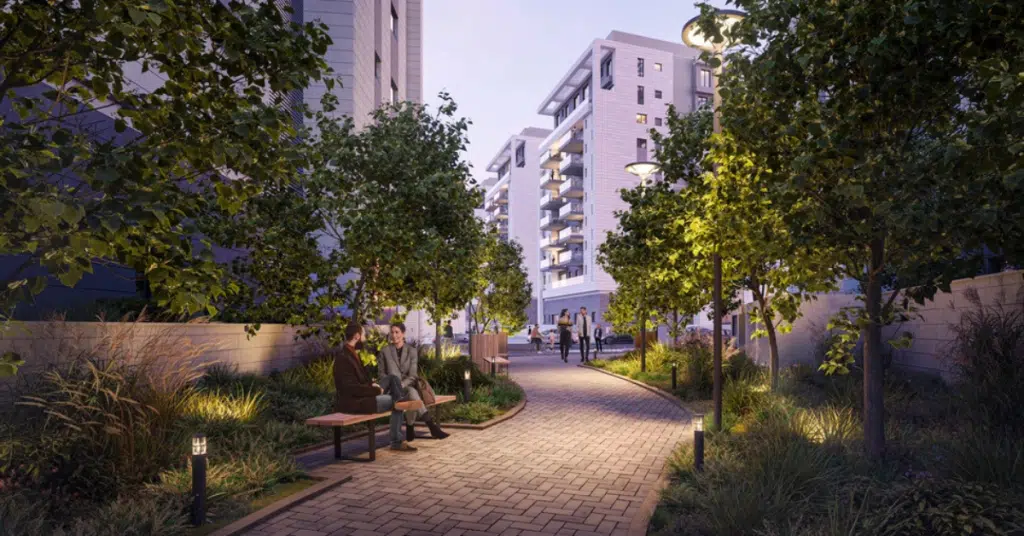 שביל מואר בפרויקט מגורים חדש בנווה מגן, עם עצים, ספסלים ואנשים נהנים מהשקט בשעות הערב.