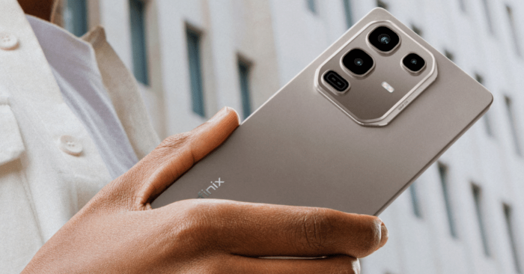 סמארטפון Infinix Note 50 בצבע כסוף ביד אוחזת, מוצג בזווית על רקע של בניין מודרני