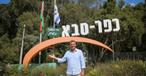 שלט הכניסה לעיר כפר סבא עם דמות מחייכת, המייצגת הזדמנות להשקעה בקרקע פרטית בצפון העיר.